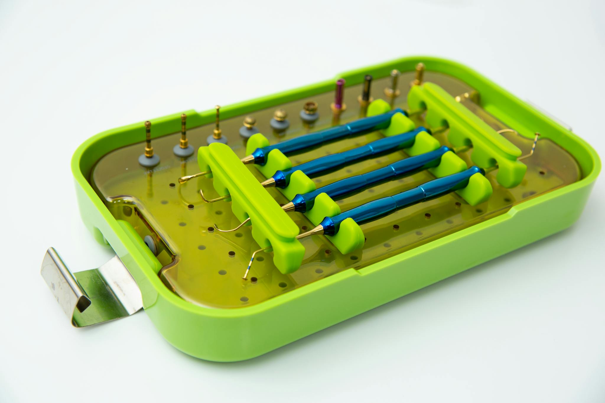 A detailed view of various dental tools in a green sterilization case for professional use.